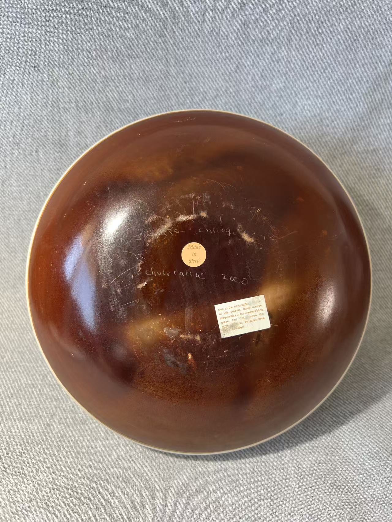 Brown ceramic bowl with visible branding on a gray fabric background