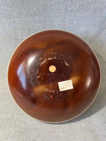 Brown ceramic bowl with visible branding on a gray fabric background
